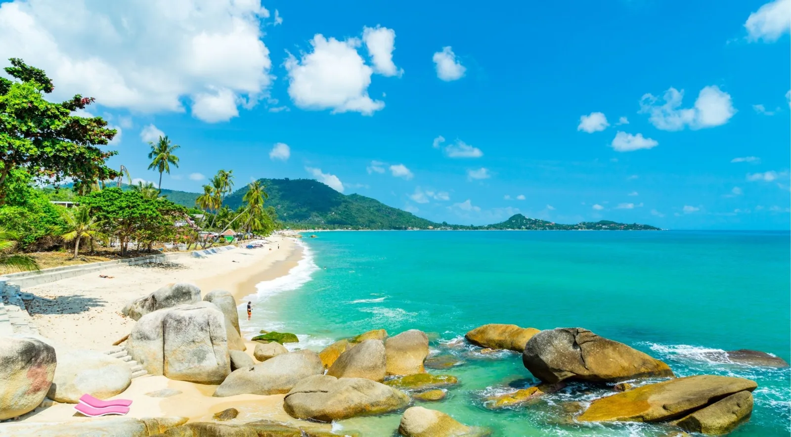 Lamai beach on Koh Samui with granite boulders in the shallows and forested hills behind