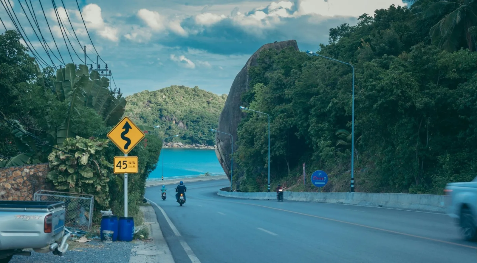 The coastal road around Koh Samui curving past a large granite boulder above turquoise water