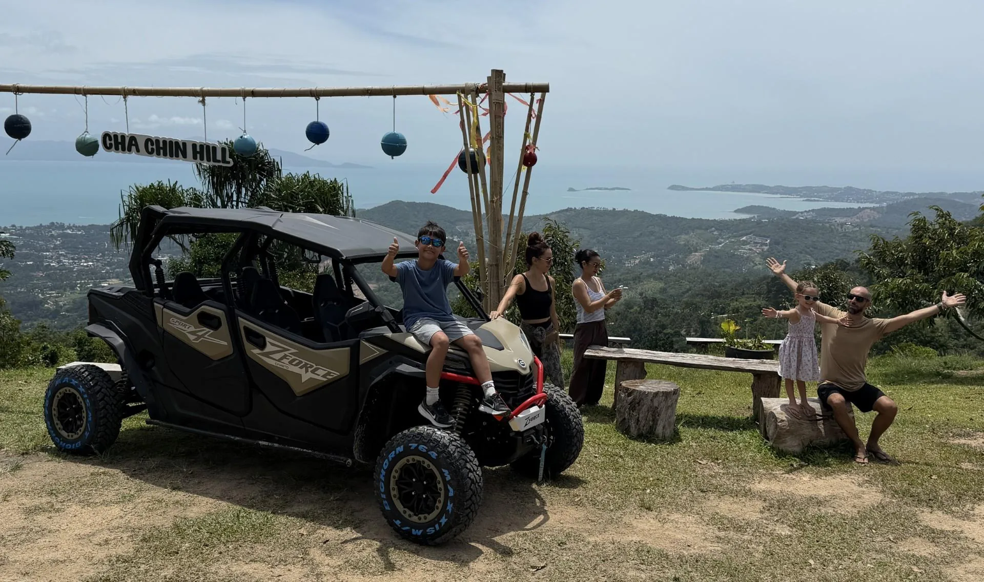 A four-seat CFMOTO buggy parked at the Cha Chin Hill viewpoint on Koh Samui with a family beside it