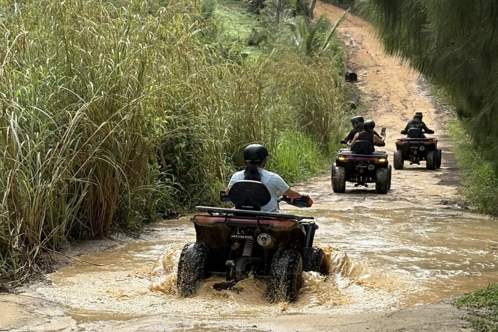 Riders on automatic quads on a red dirt mountain trail behind Nathon, Koh Samui