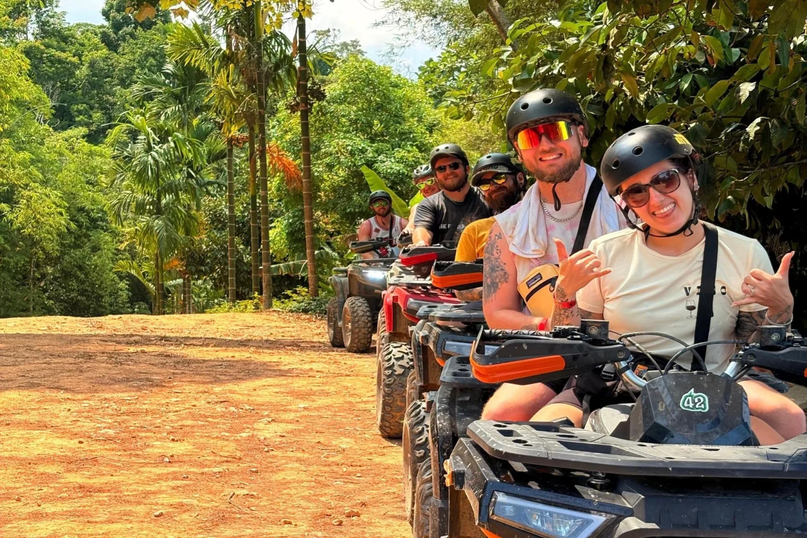 A convoy of ATVs waiting under palms on a Koh Samui jungle trail, guide at the front