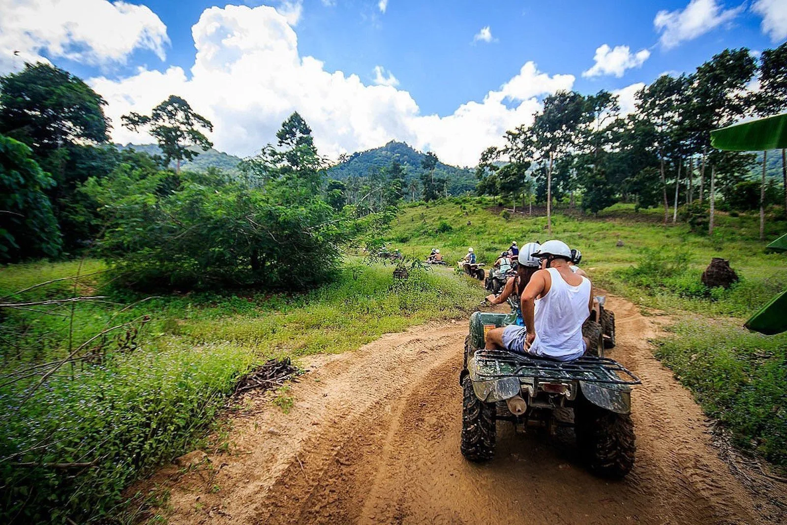 Riders on automatic quad bikes following a guide along a dirt track in Koh Samui's interior